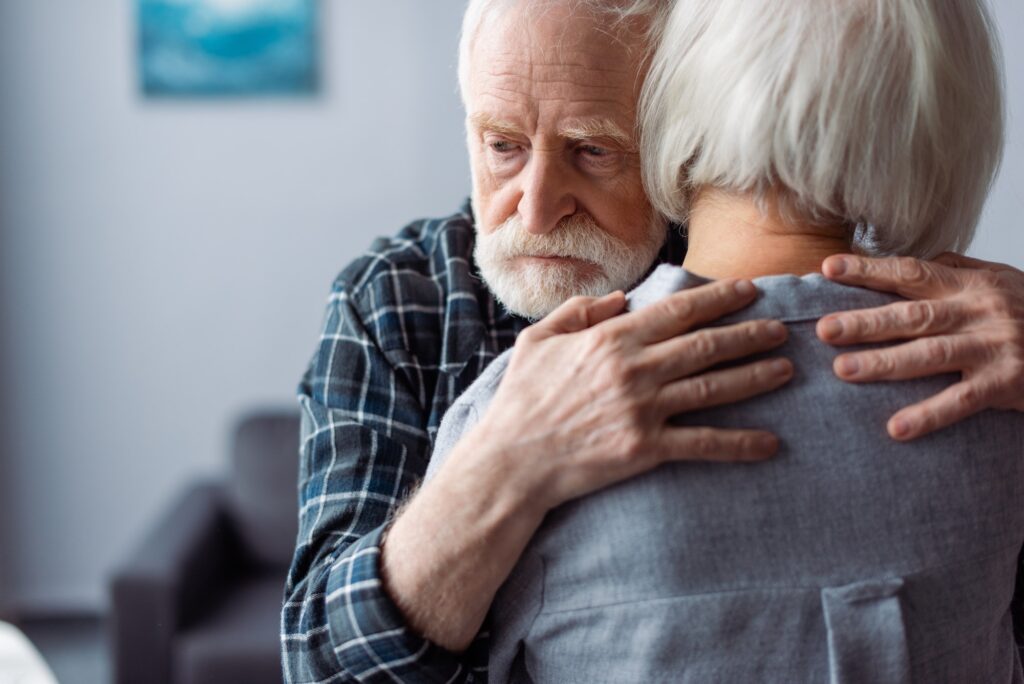 back view of senior woman hugged by husband, sick on dementia